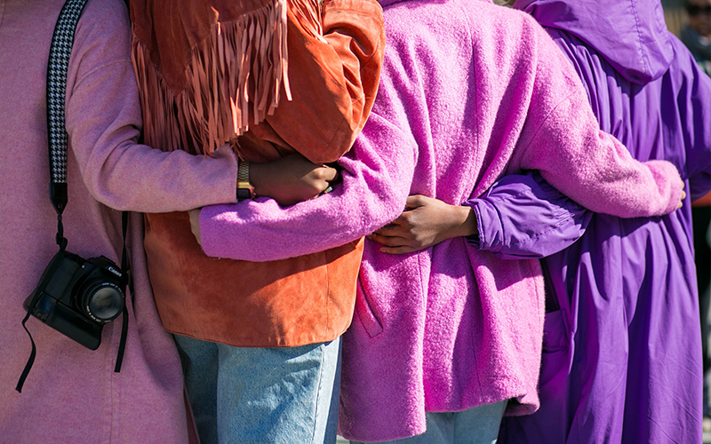women in colourful clothes with arms around each other