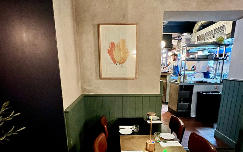 interior of cin cin in hove, with a covered table in the foreground and a picture in the background 