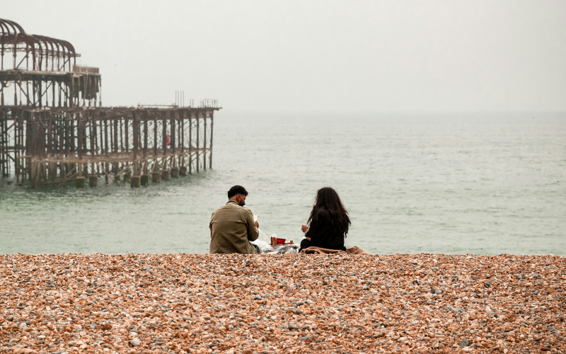 brighton pier and beach with couple sitting on stones